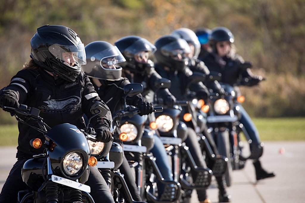 Jeune homme portant des vêtements en cuir avec sa Harley Davidson